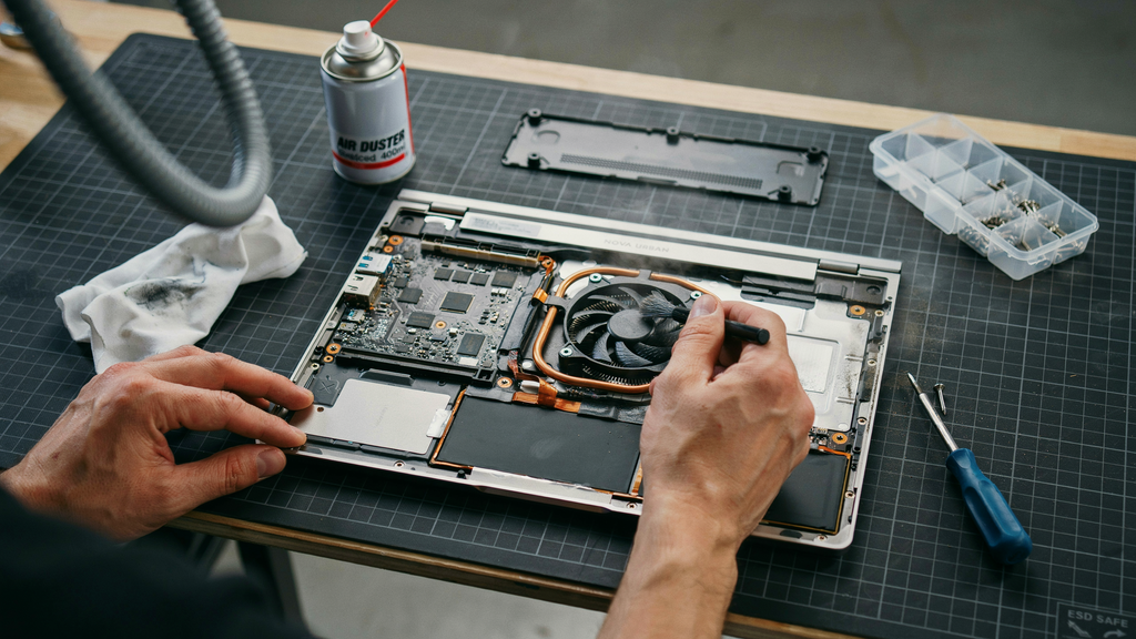 Notebook aberto mostrando componentes internos sendo limpos